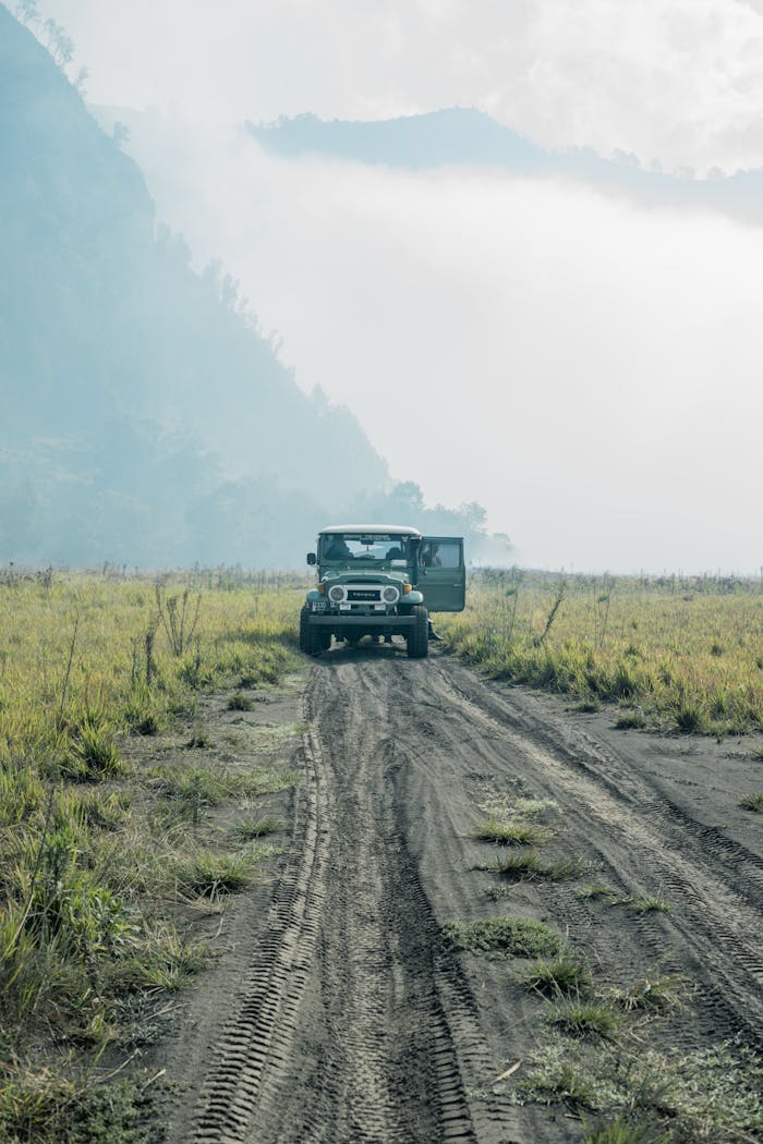 Explore the rugged beauty of East Java's countryside with a jeep in a foggy, picturesque setting.