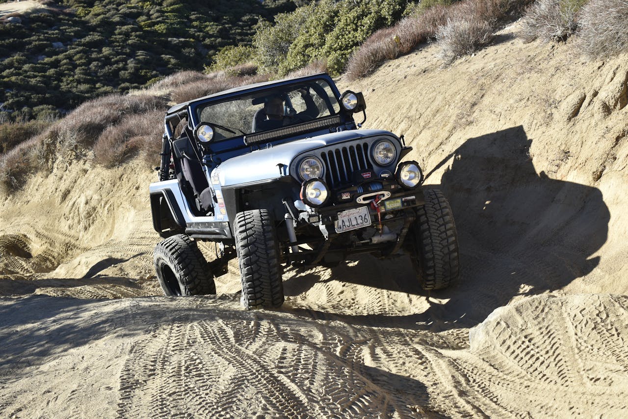 A rugged off-road vehicle navigating challenging sandy trails in mountainous terrain.