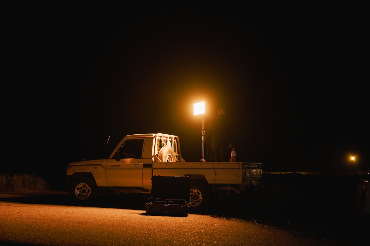 who-we-are A white truck with a spotlight illuminating the road at night, creating a dramatic scene.