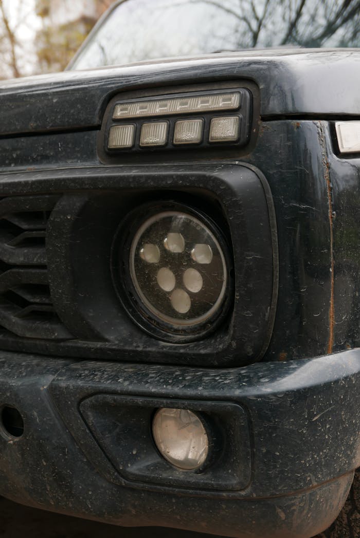 Close-up view of a dirty car headlight featuring distinctive livery and design details.